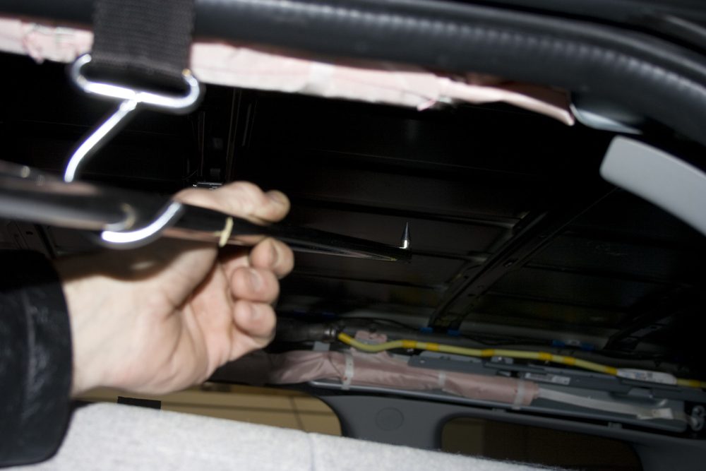 A technician using a tool to reach behind a panel